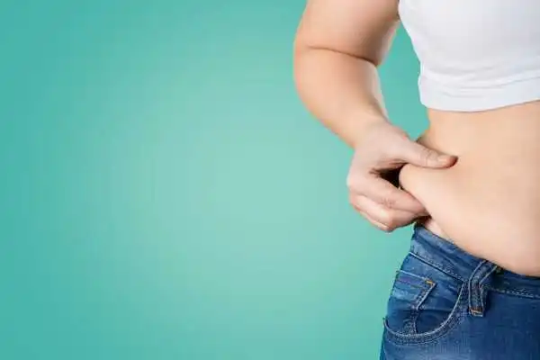 Image of woman pinching her love handles to show weight gain Balsall